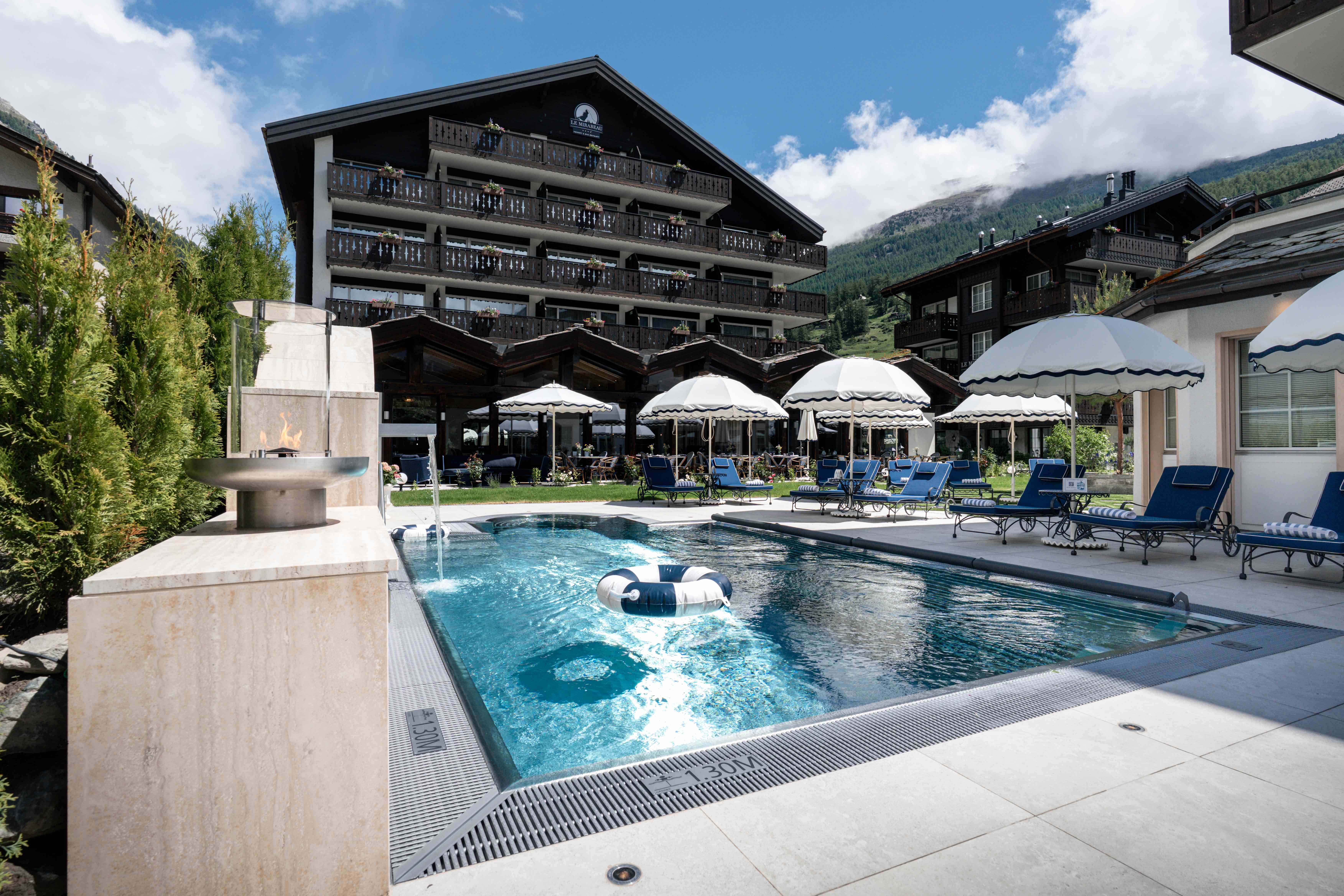 Aussenpool des Le Mirabeau mit Sonnenschirmen und Blick auf das Chalet-Hotel